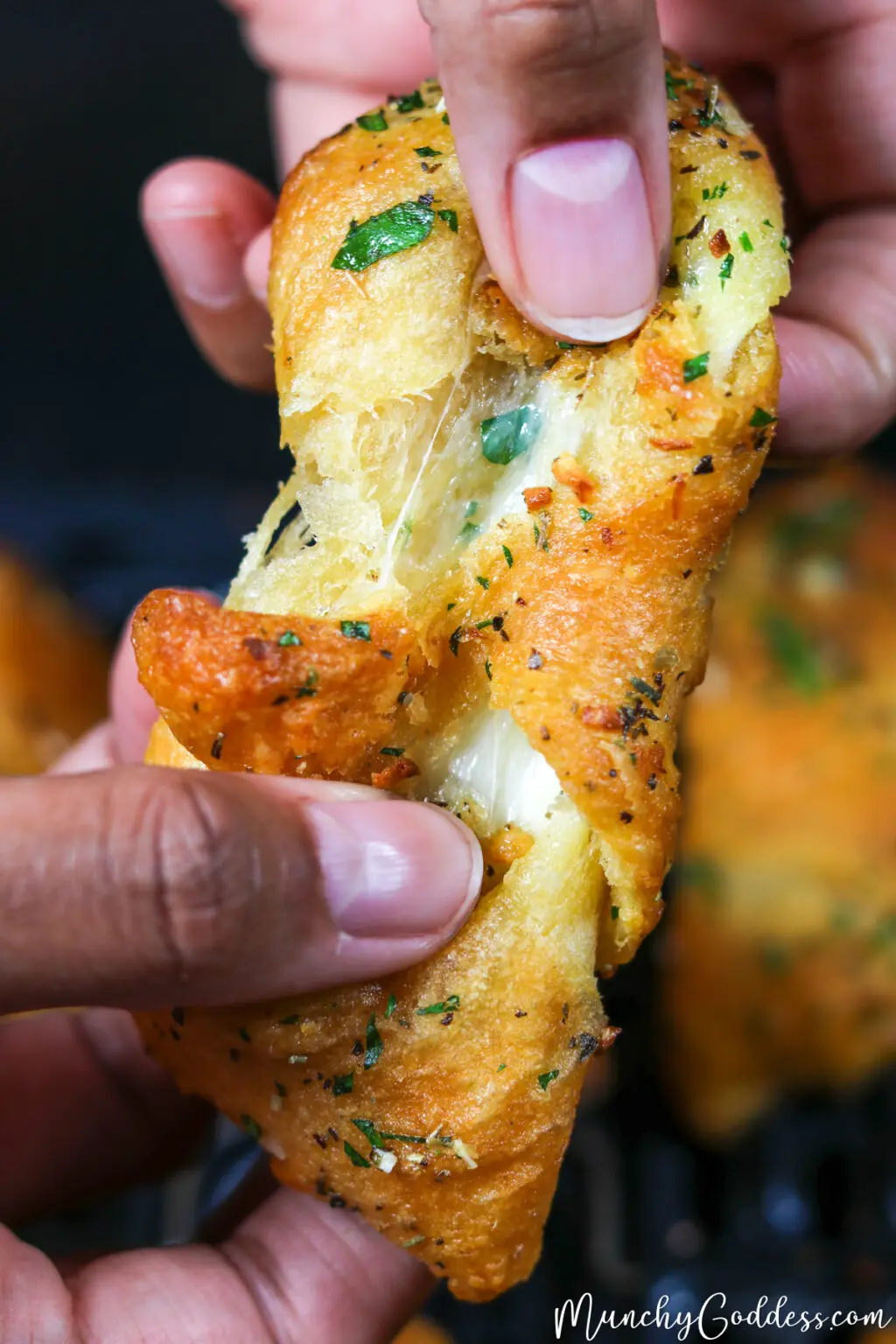 Air fryer cheesy garlic crescent rolls being pulled apart with hands.