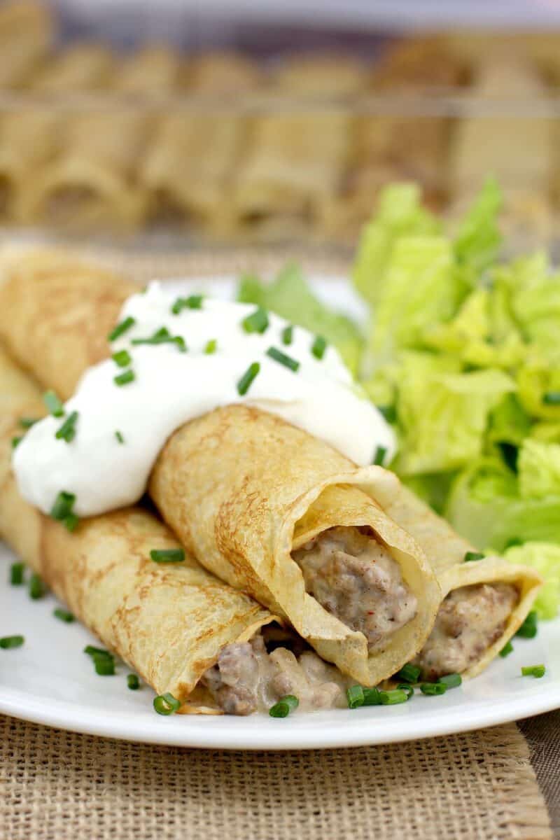 Ground beef stroganoff stuffed crepes rolled on a plate.