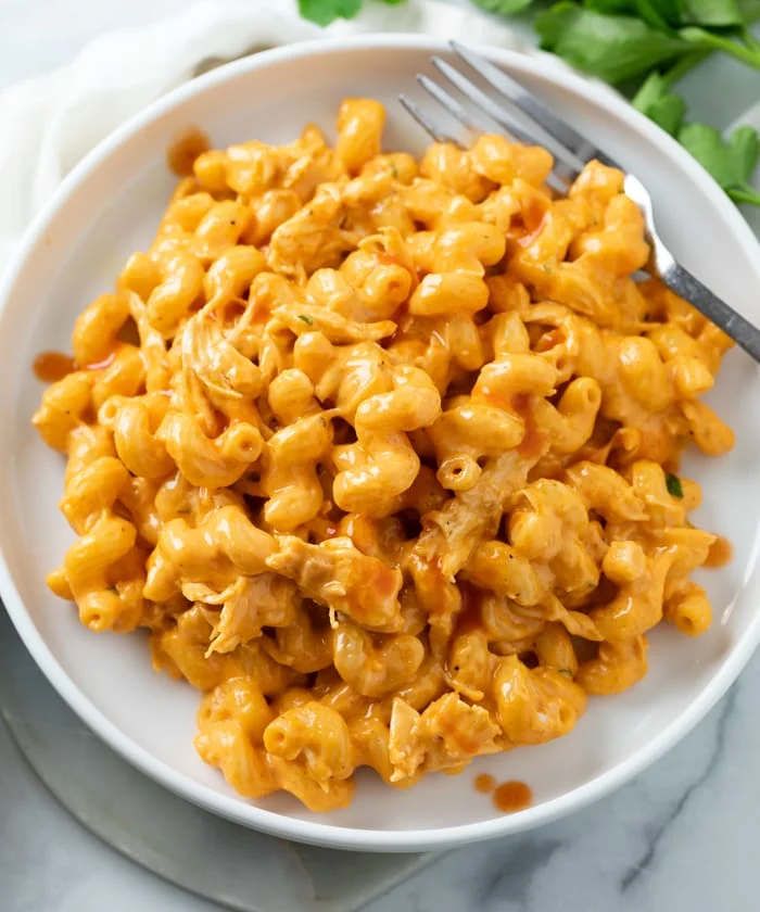 Buffalo chicken mac and cheese on a white plate with fork.