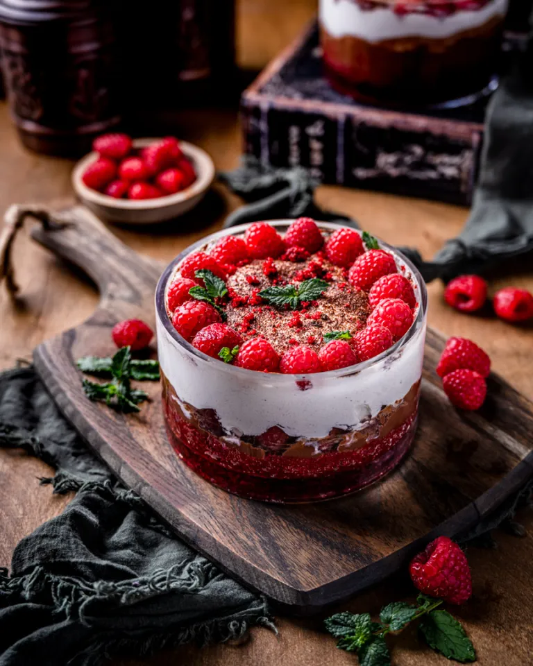 Chocolate raspberry red velvet trifle on wooden cutting board.