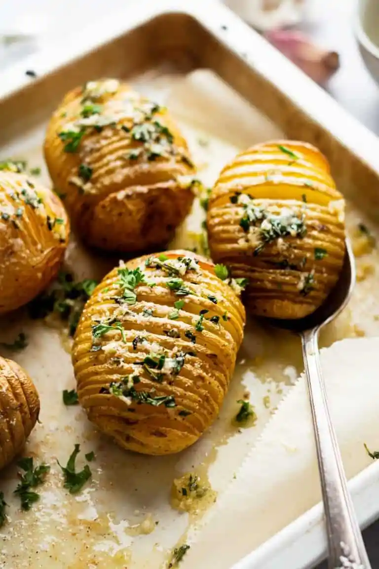 Hasselback potatoes on a white serving dish.