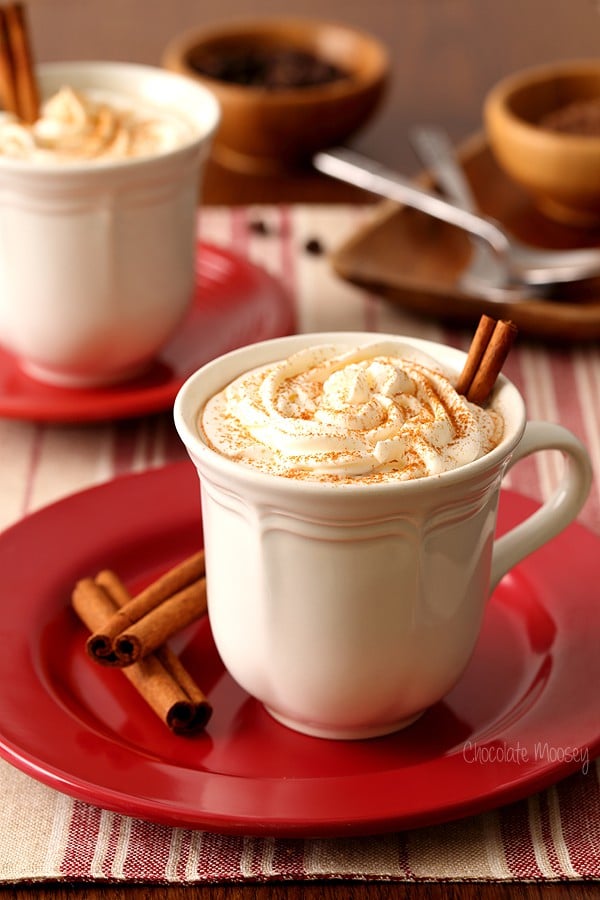 Mexican Mocha drink in a mug on a red saucer with cinnamon sticks.