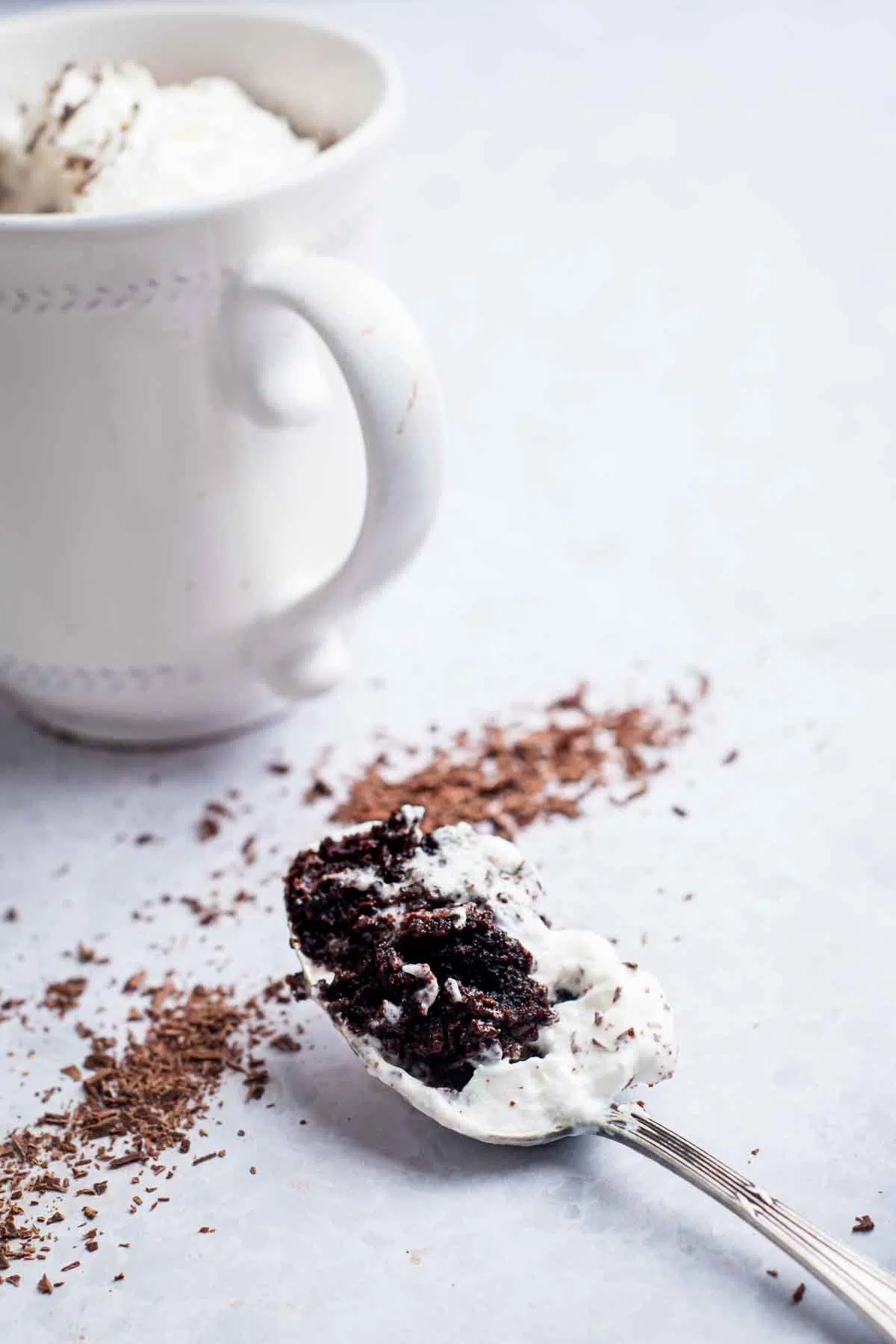 Spoonful of mug cake with mug in the background.