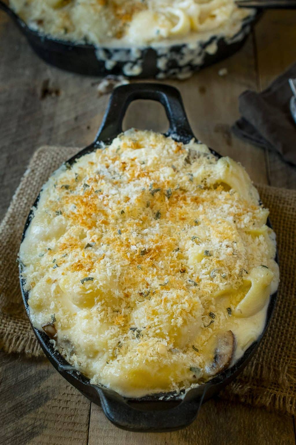 Mushroom, sage mac and cheese with a crispy panko breadcrumb topping in a cast iron pan.