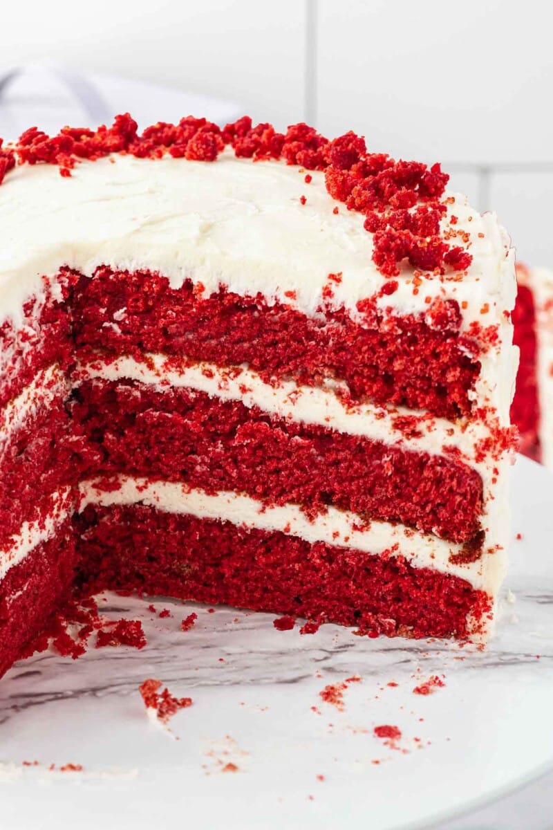 Classic red velvet cake with slice removed.