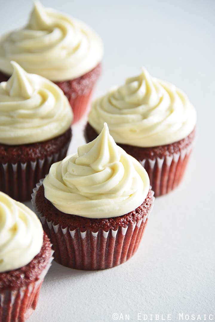 Bunch of red velvet cupcakes with cream cheese frosting.