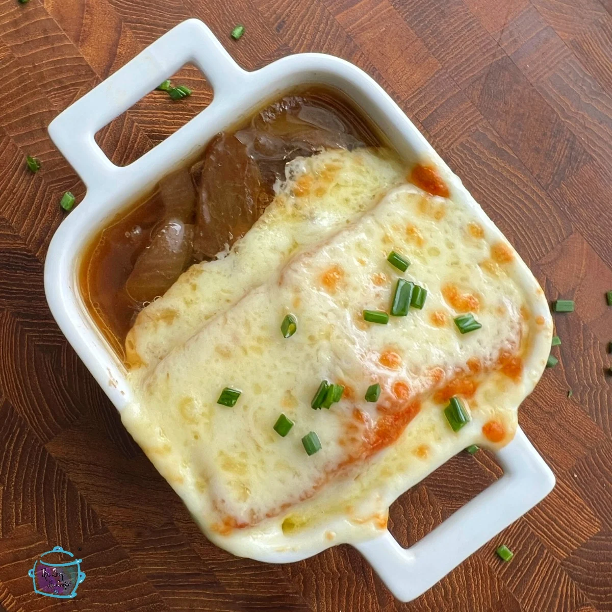 Slow cooker caramelized French onion soup in a white serving dish.