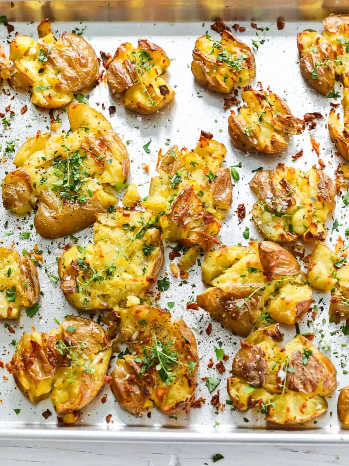 Crispy smashed potatoes on a baking pan.