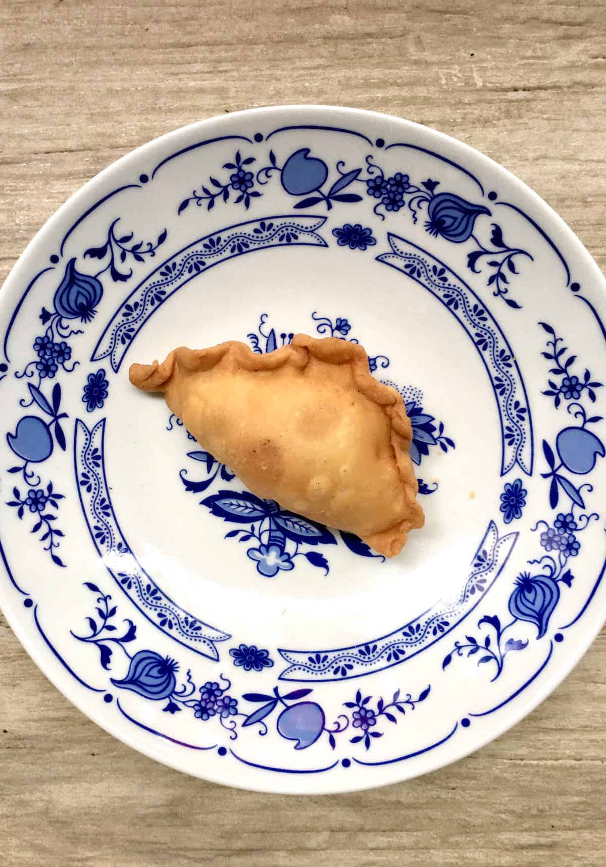 Karipap, aka curry puff, on a decorative white and blue plate.