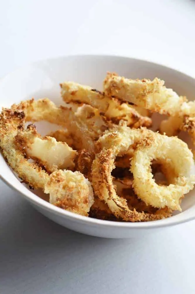 Air fryer onion rings in a white bowl.