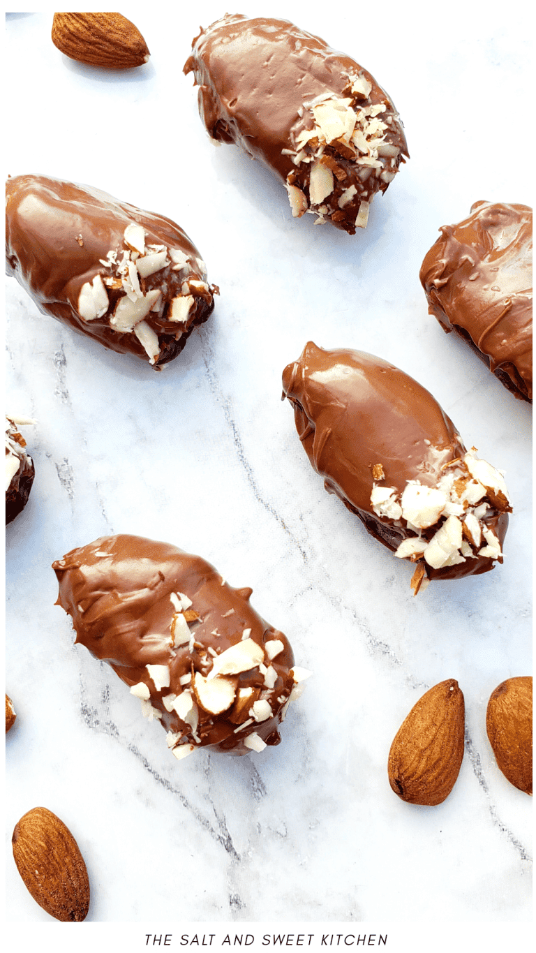 Chocolate covered dates with almonds on a white background.