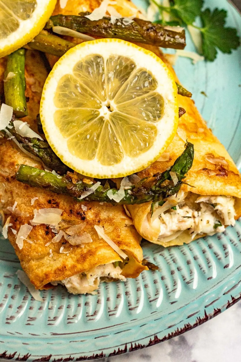 Chicken asparagus crepe with asparagus and lemon on a plate.