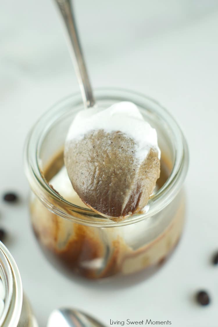 Spoonful of chocolate and coffee custard with whipped cream on top in a jar.