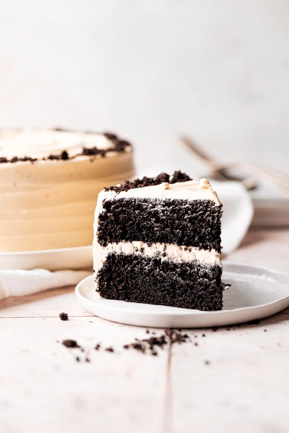 Chocolate coffee cake slice on a plate with whole cake in the background.