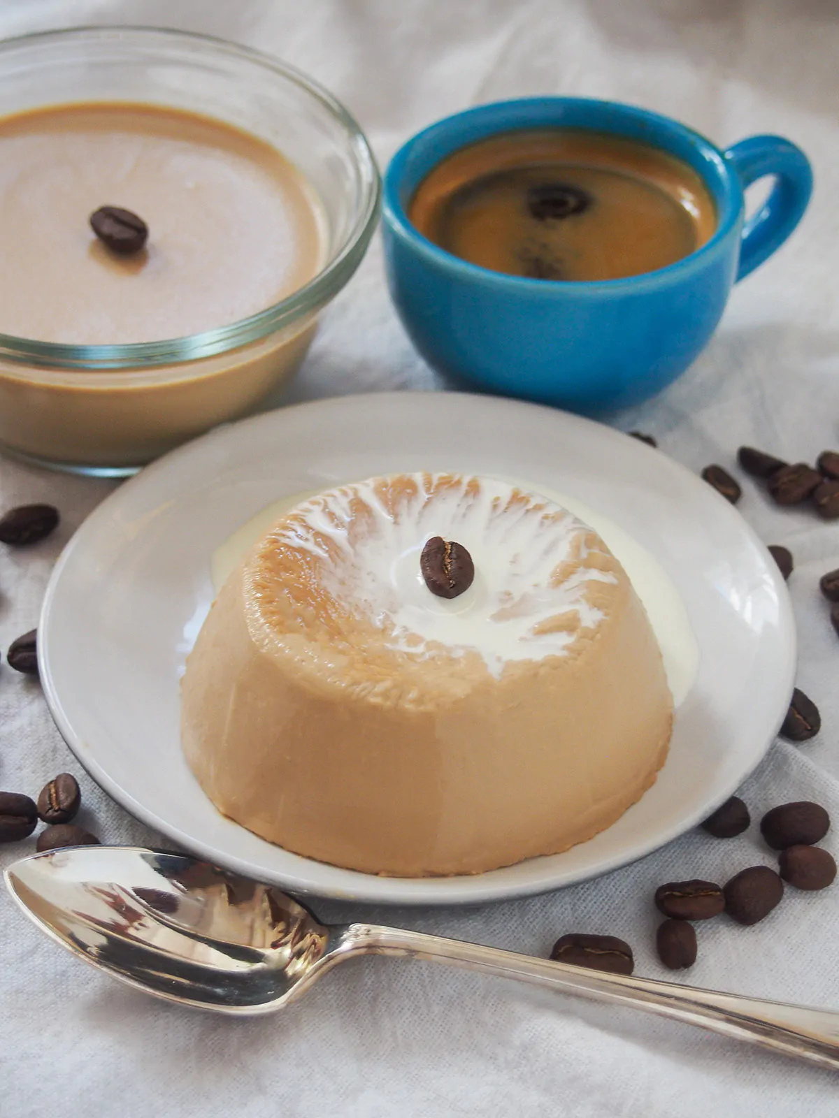 Coffee panna cotta on a plate with coffee and another serving in the background.