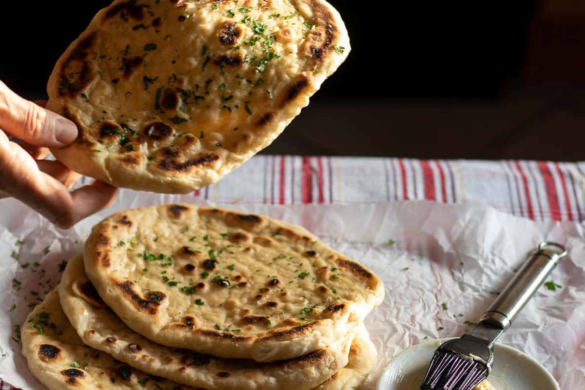 Stack of homemade garlic butter naan brad on parchment paper.