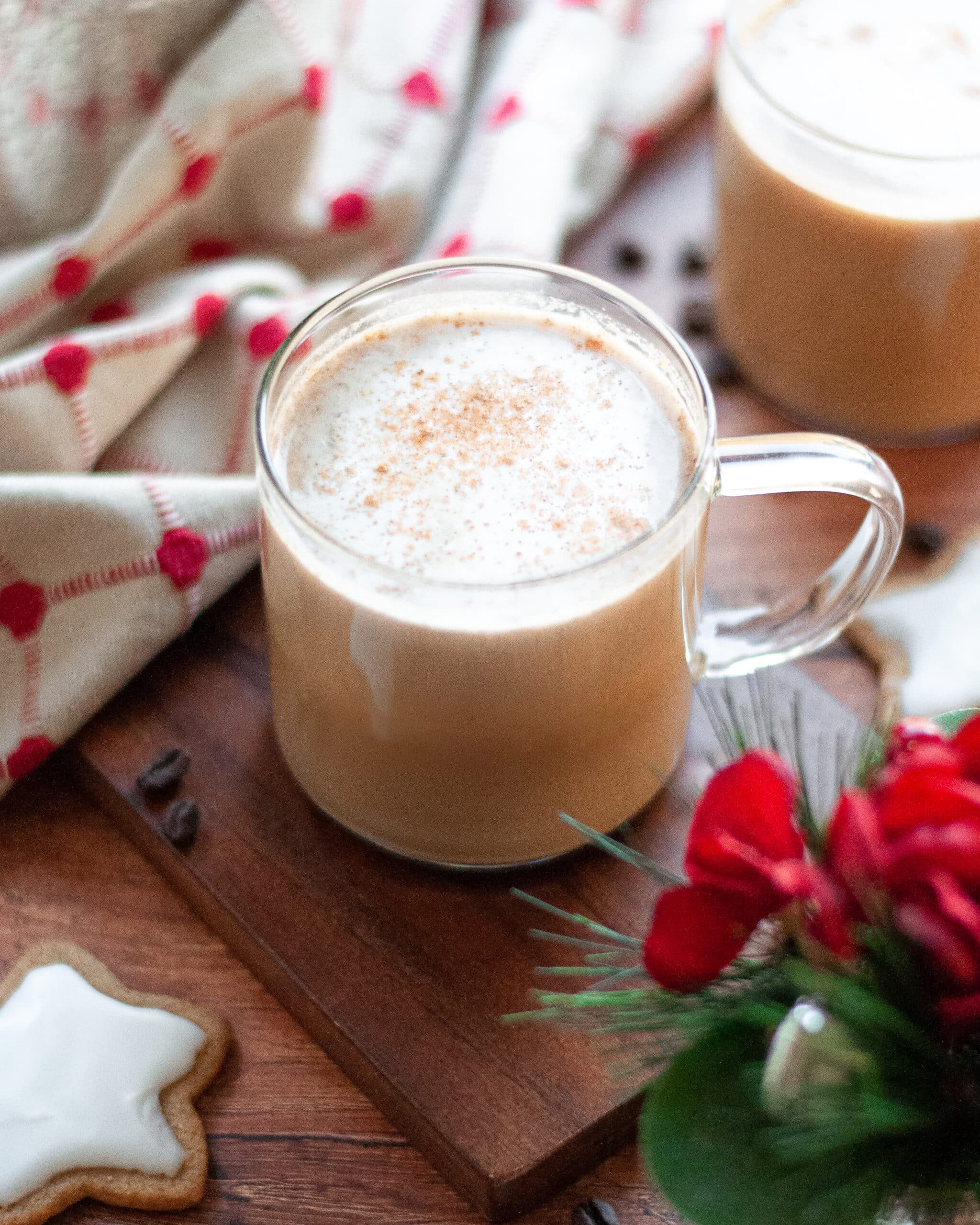 Gingerbread coffee in glass mug with flowers in foreground.