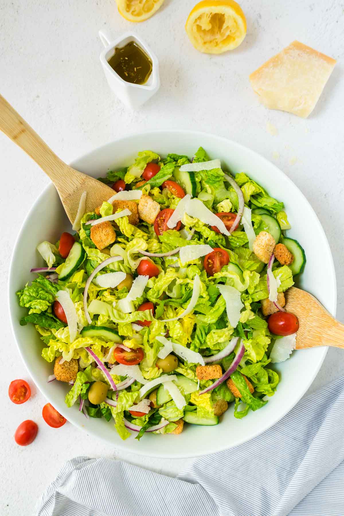 Tossed simple salad in a bowl with ingredients in background.