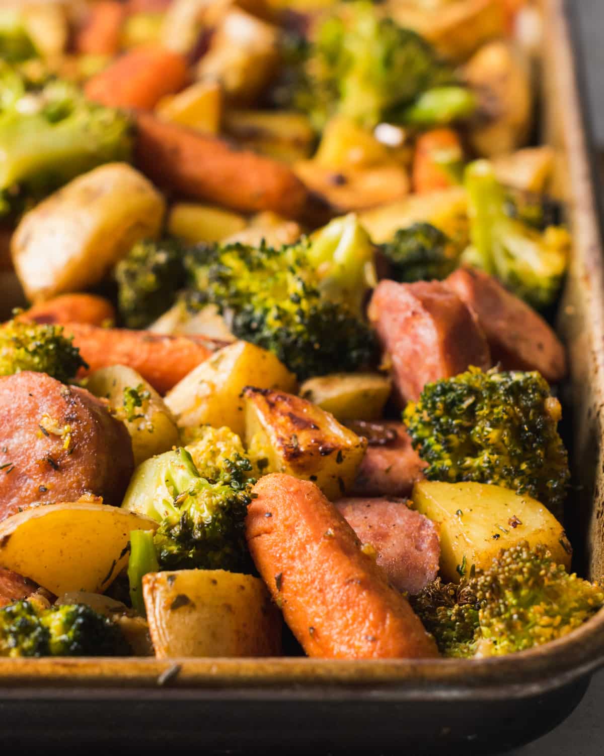Baked sausage and vegetables on a sheet pan.