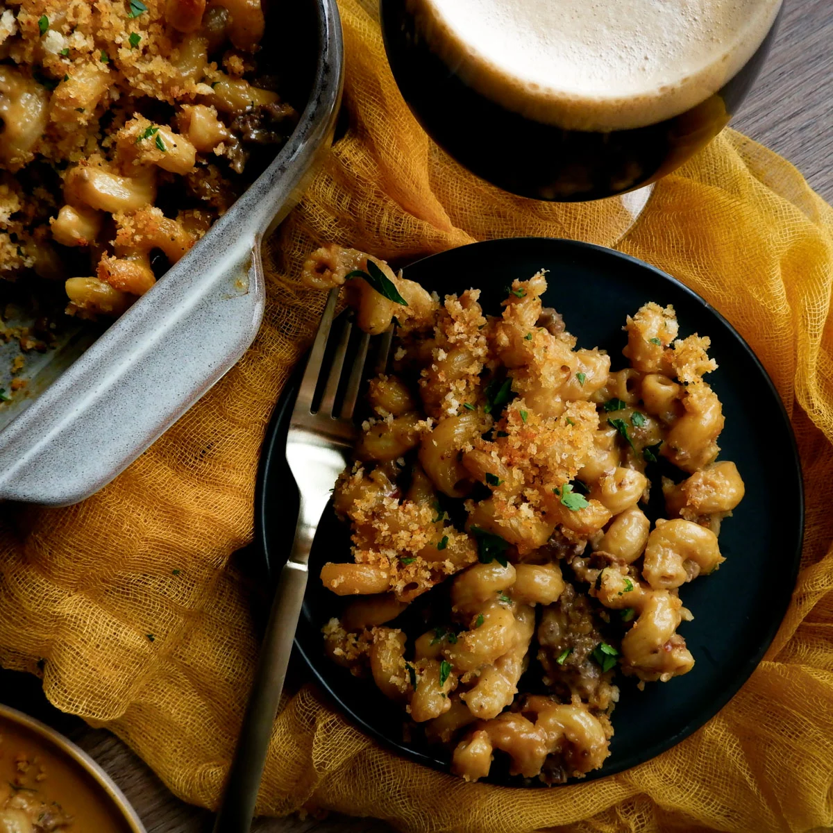 Serving of stout mac and cheese with beer and casserole dish.