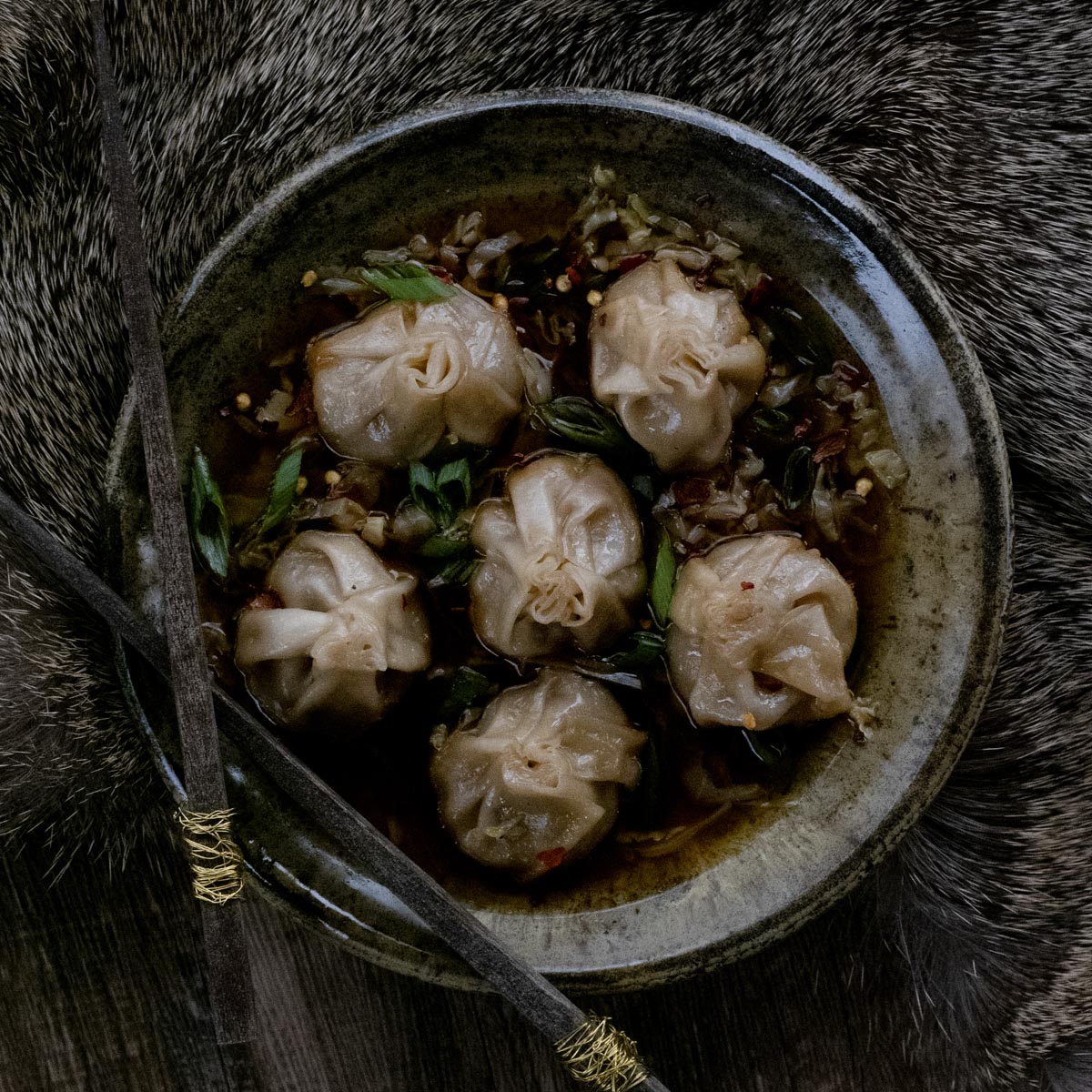 Bowl of venison dumpling soup with chopsticks on deer hide.