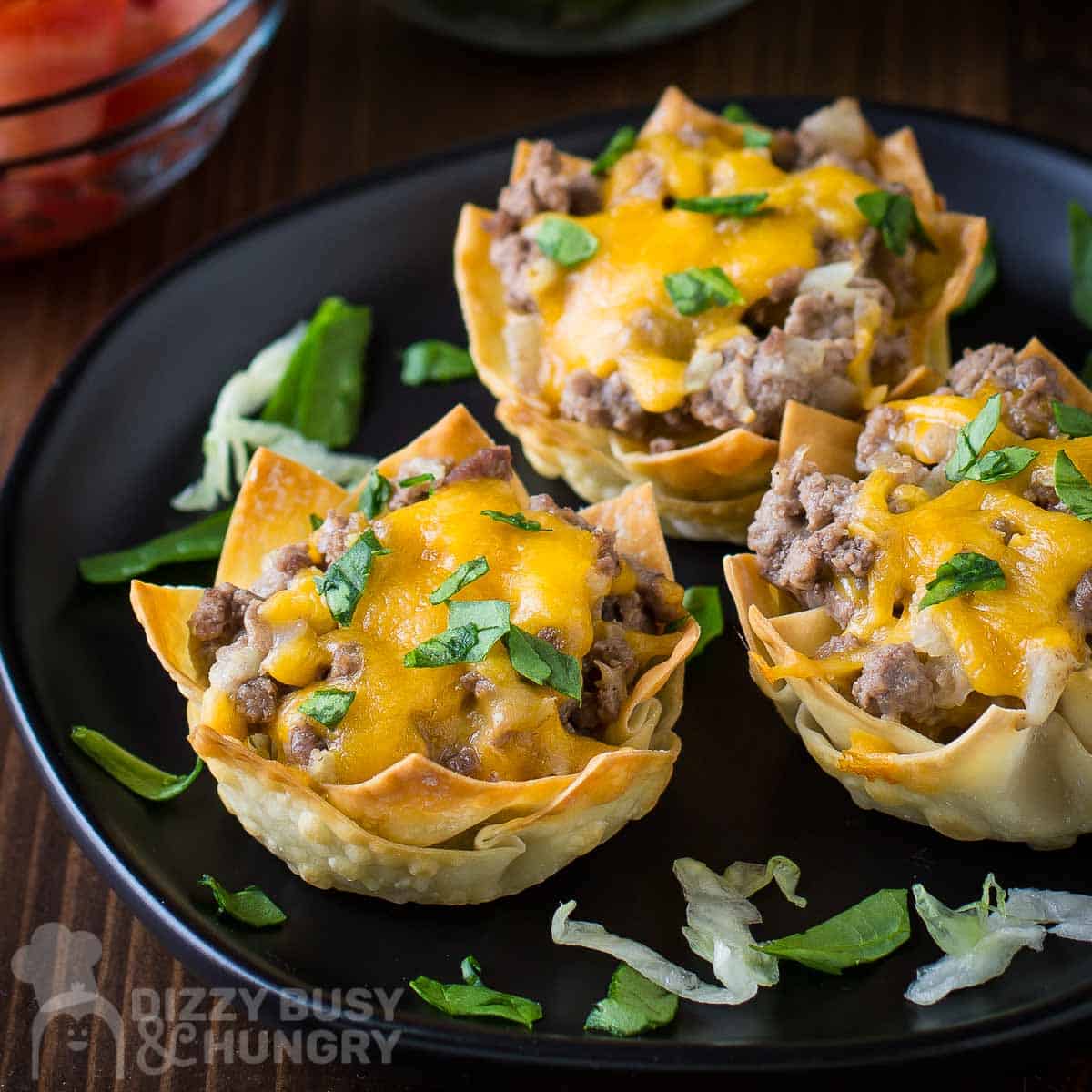 Wonton Cheeseburger cups on a black plate.