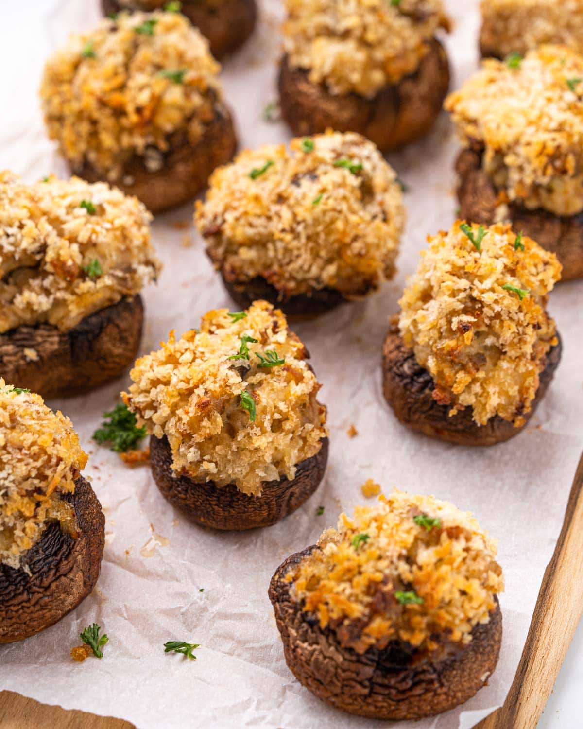 Air fryer stuffed mushrooms aligned on parchment paper.