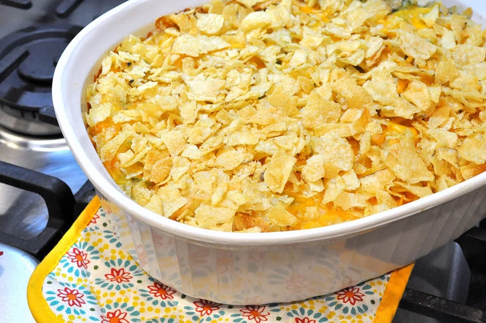 Cheesy tuna casserole with potato chip topping in baking dish.