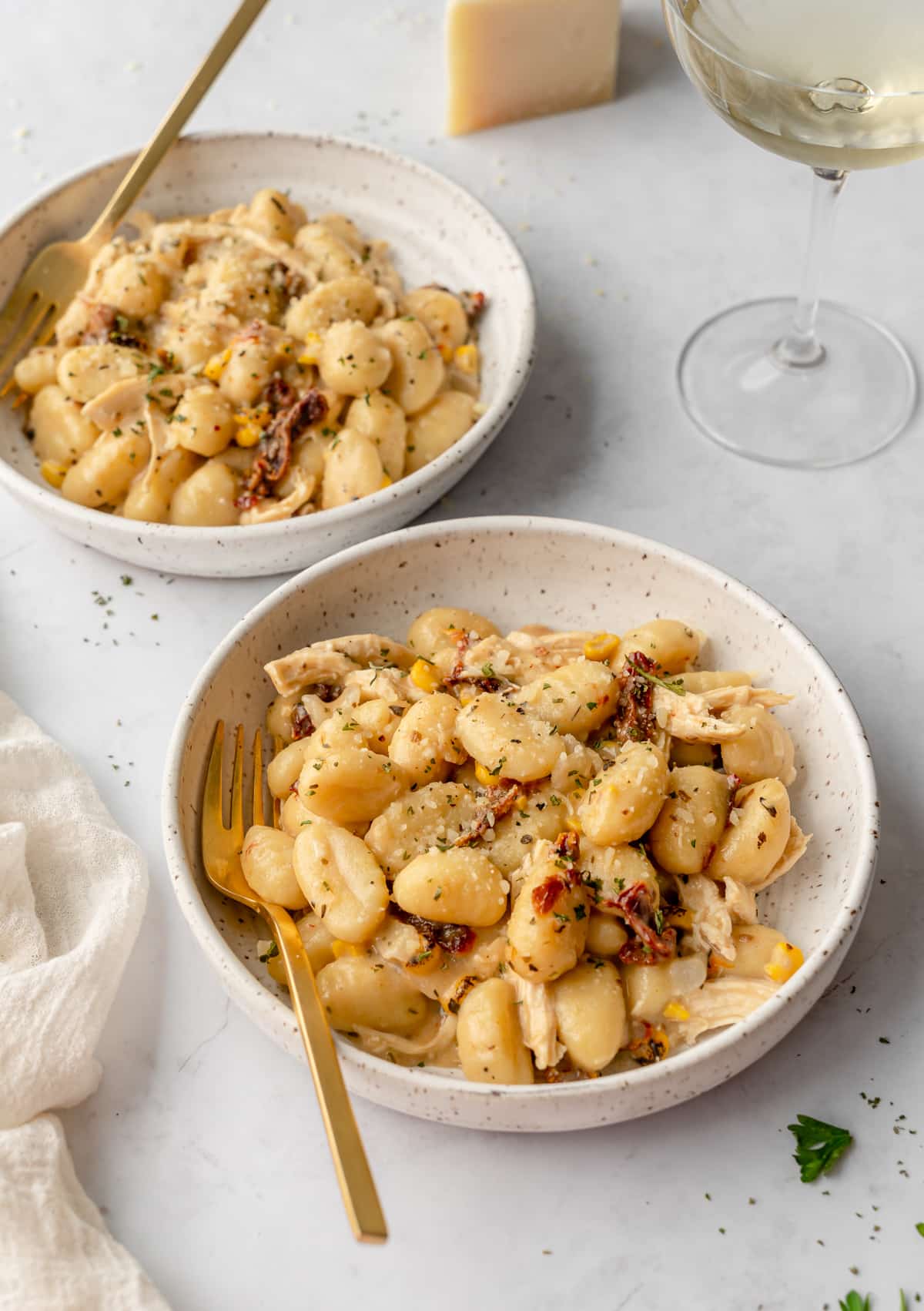 One pot cream gnocchi served in bowls with wine glass behind it.