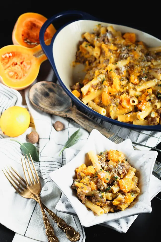 Serving of sausage butternut squash pasta in a white bowl with forks around.