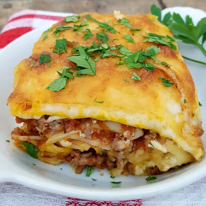 Egg noodle lasagna with herbs on a white plate.