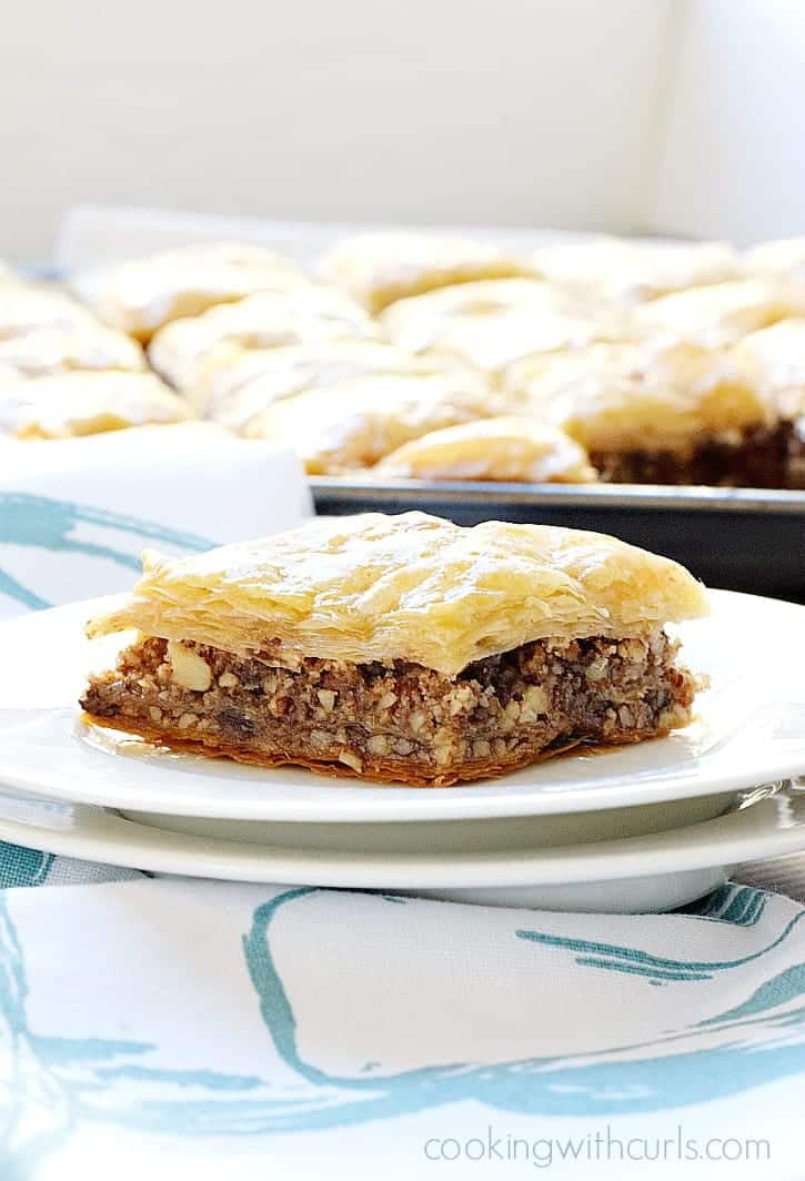 Piece of chocolate baklava on a white plate with more in the background.