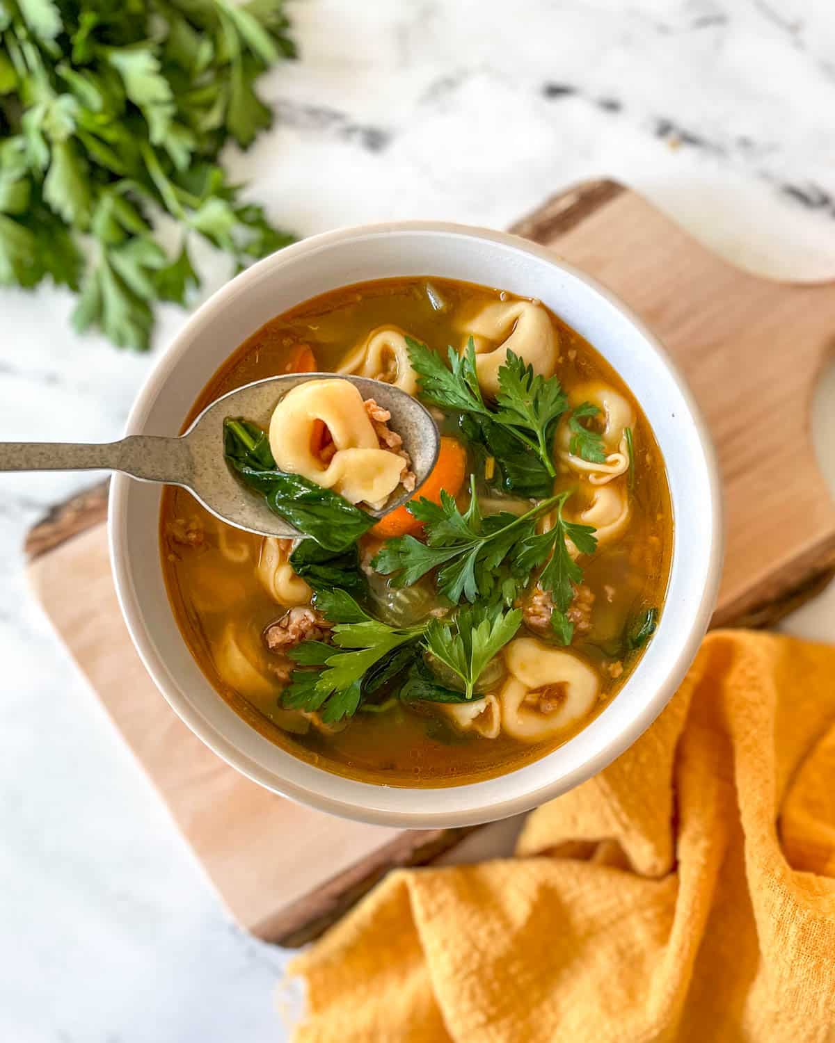 Spoonful of Instant pot tortellini soup dipping into a bowl full.