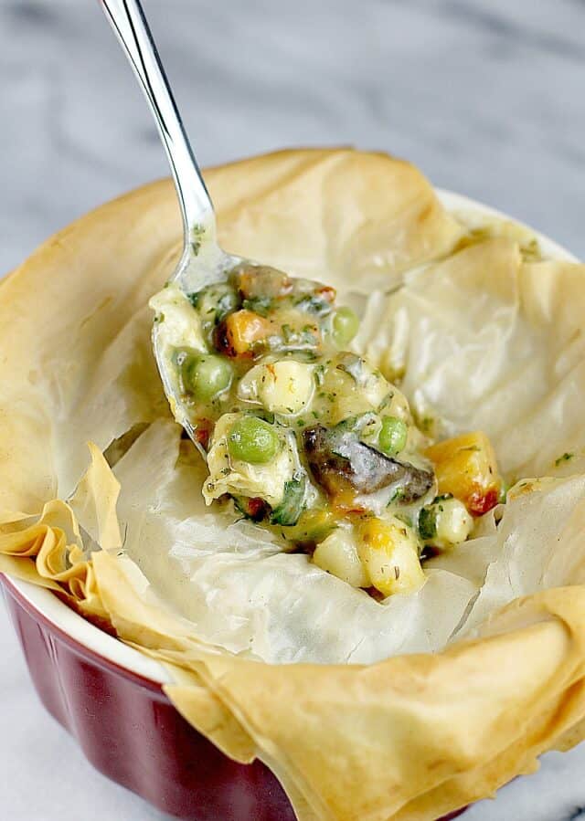 Spoon dipping into phyllo dough topped Italian veggie pot pie.