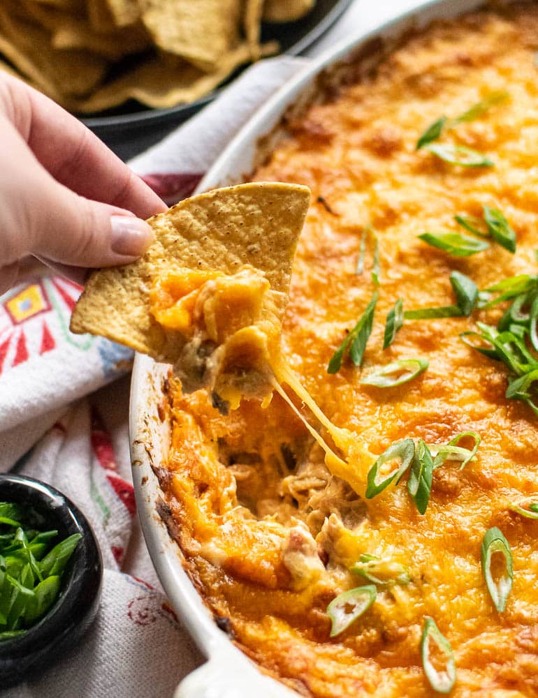 Hand dipping chip into dish filled with Mexican shredded chicken dip.