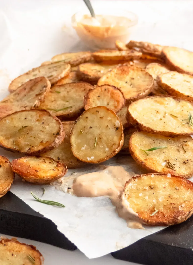 A mountain of crispy oven roasted potatoes with dipping sauce.