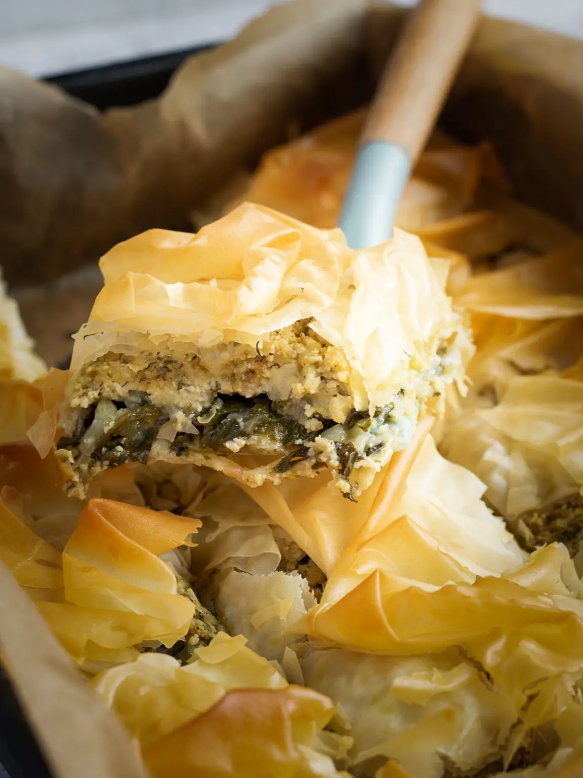 Spatula lifting a slice of Greek spinach pie.