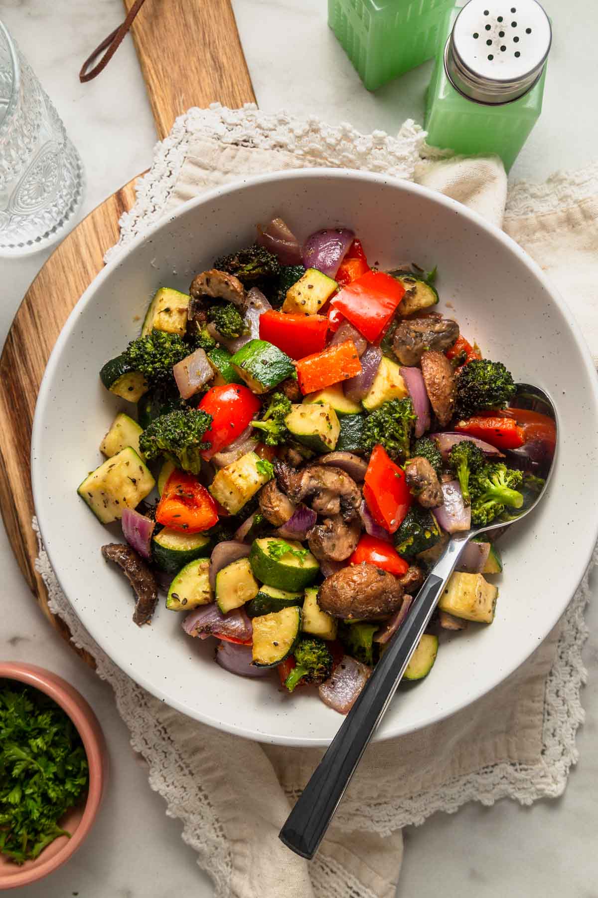 Air fryer roasted vegetables with a spoon in a white bowl.