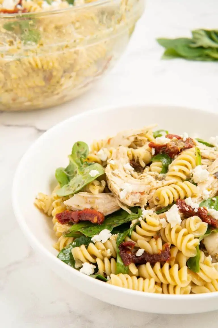 Chicken pesto pasta salad in a white bowl. 