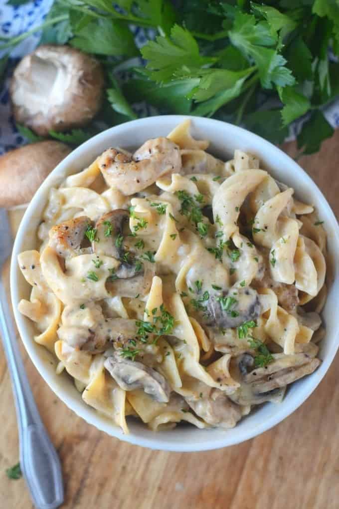 Chicken stroganoff with a sprinkle of herbs in a white bowl.