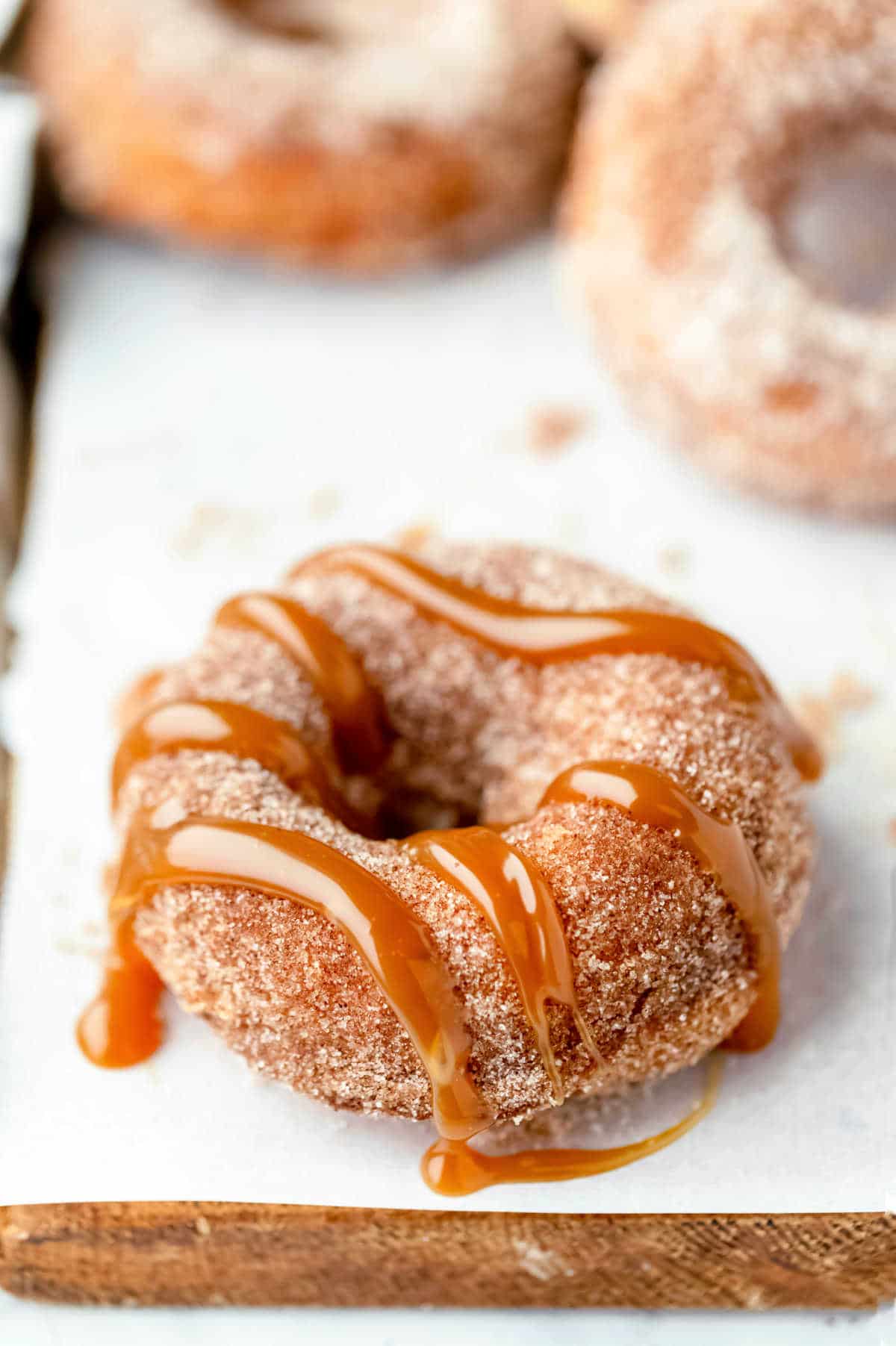 Churro donut with caramel drizzle on parchment paper.