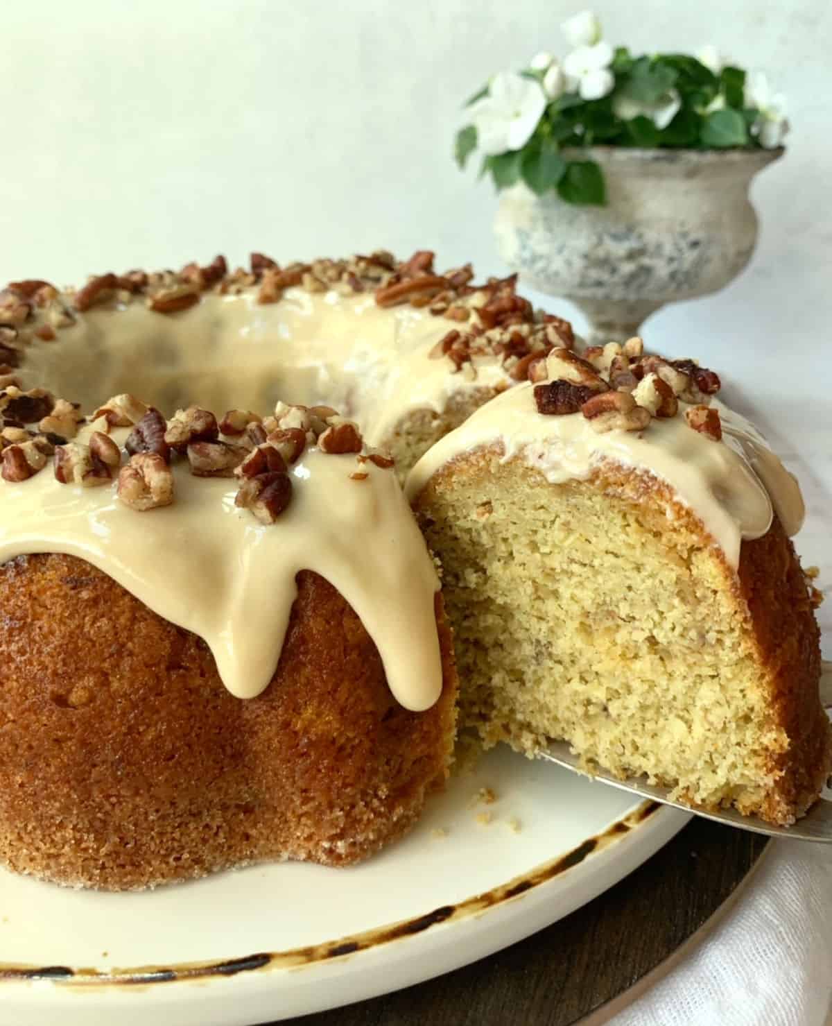 Easy banana caramel cake on a platter with a slice pulled out.