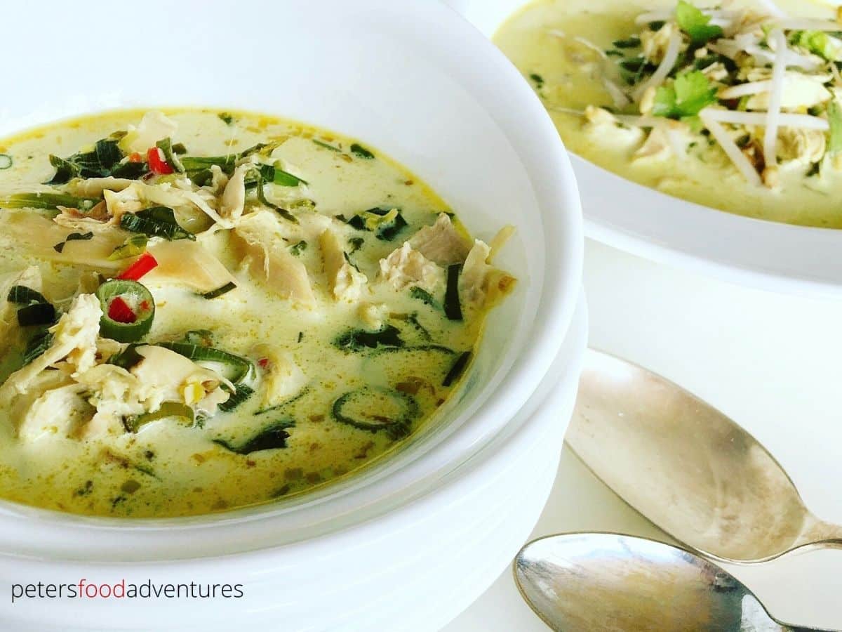 Tom kha gai soup served in white bowls with spoons in the image.