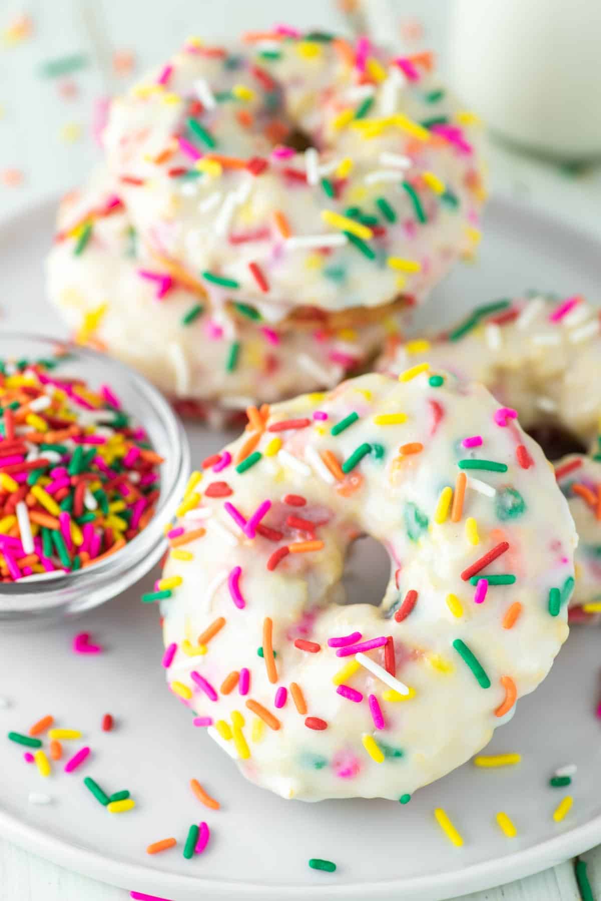 Stack of sprinkle filled donuts with glaze and more sprinkles.