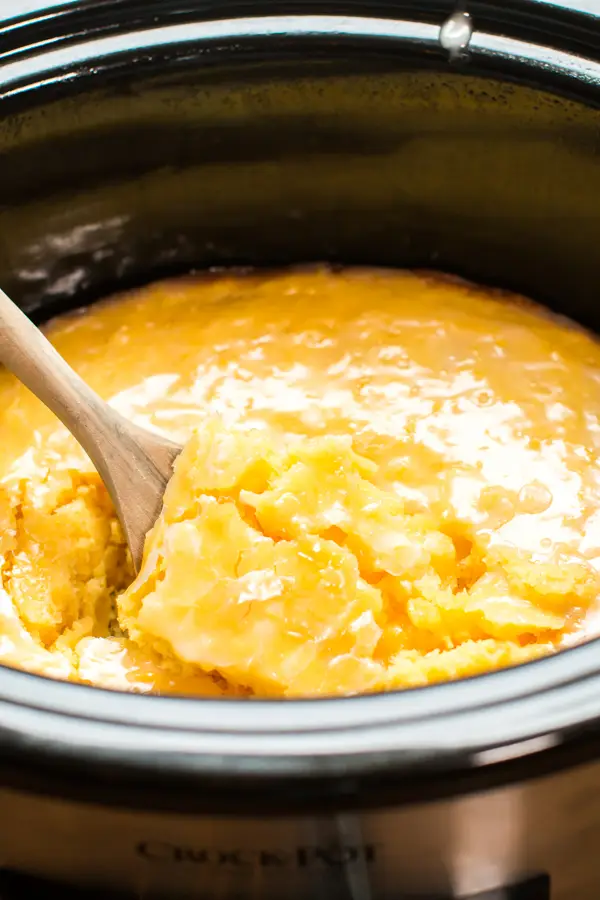 Slow cooker lemon spoon cake in the slow cooker with wooden spoon.