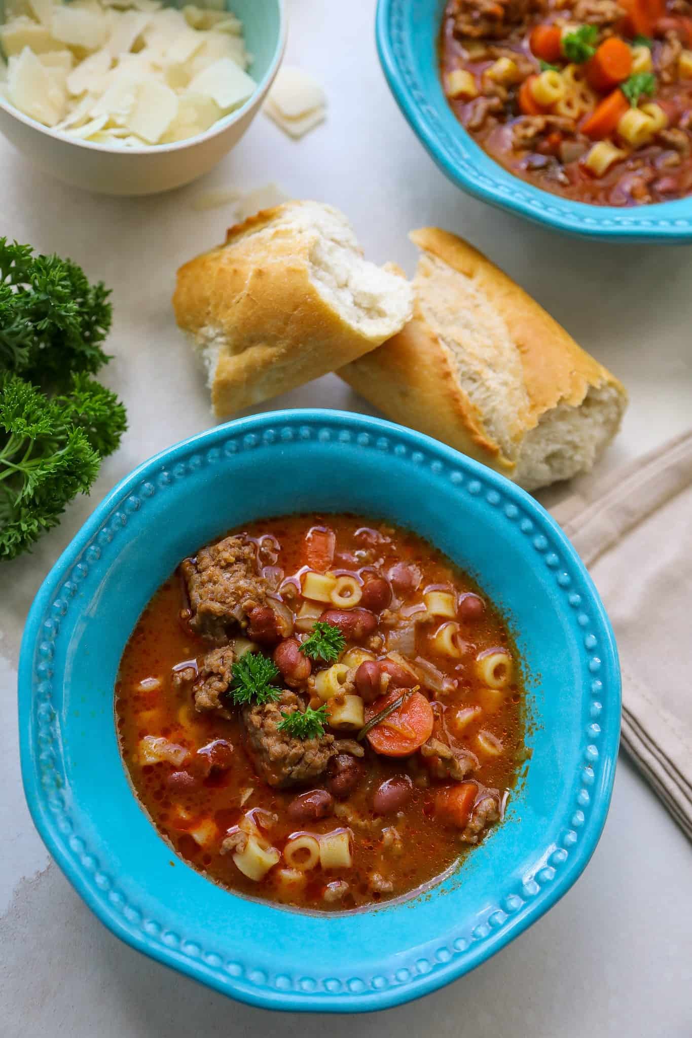 Pasta fagioli in a blue bowl with crusty bread.