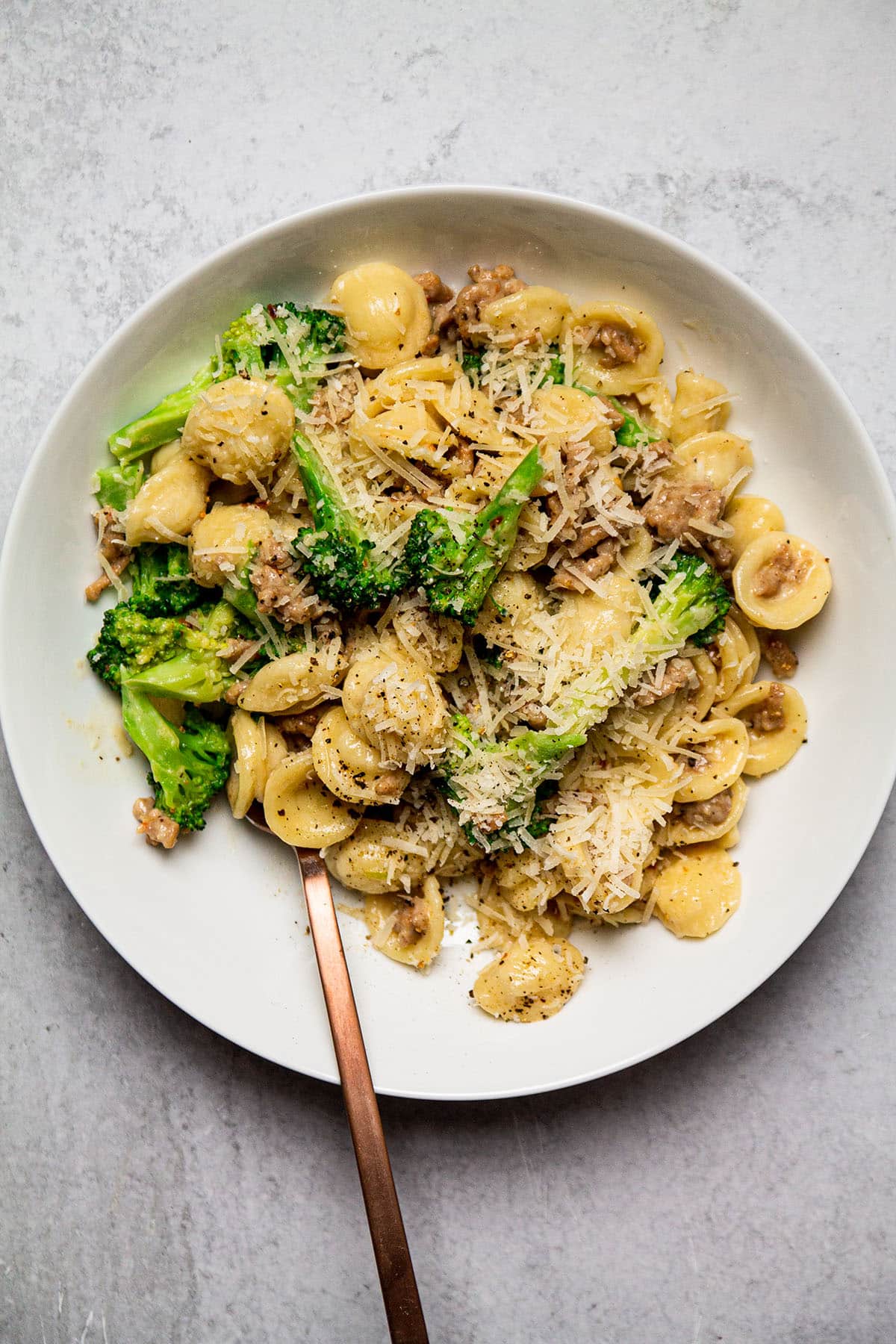 Spicy sausage and broccoli orecchiette  with a fork on a white plate.