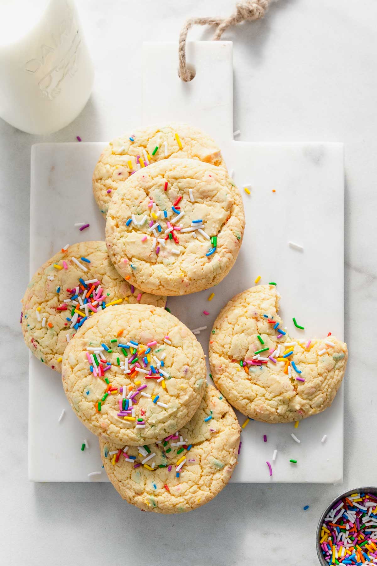 Yellow cake mix cookies with sprinkles on a marble platter.