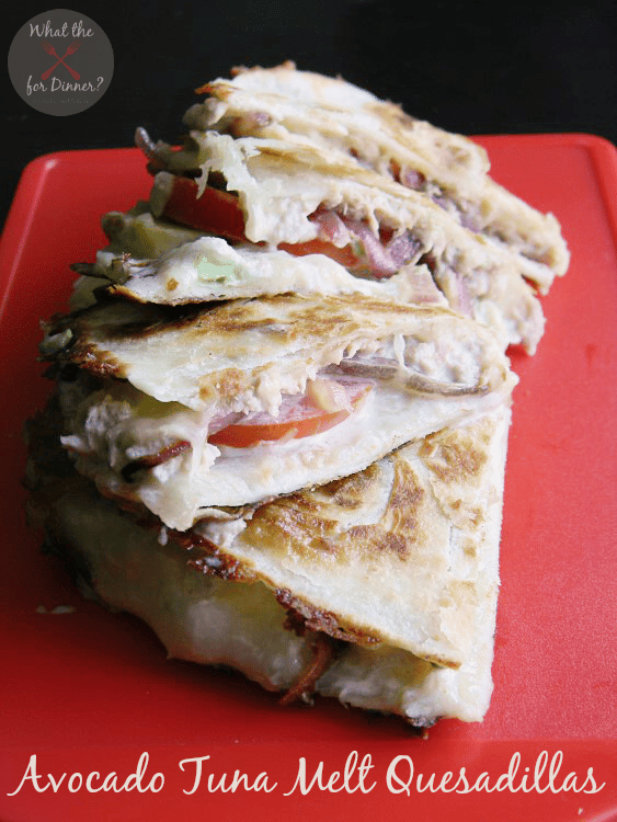 Tuna melt quesadillas with creamy avocado on a red platter.