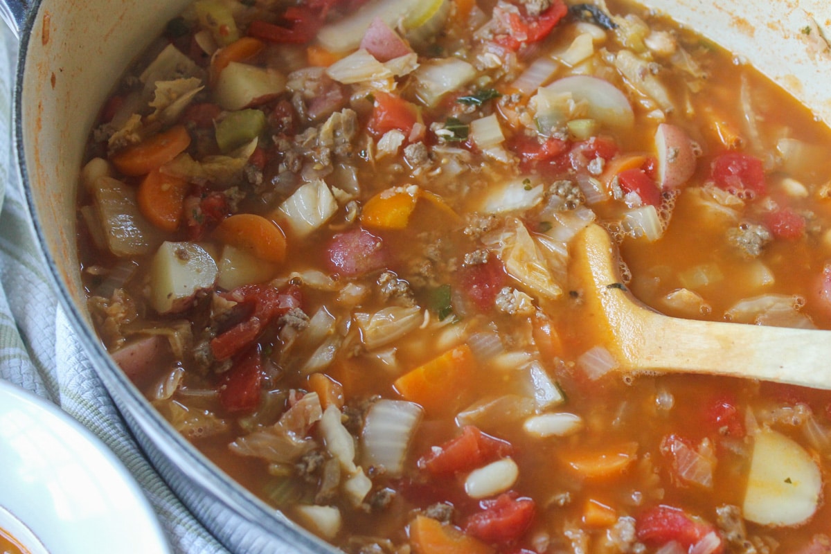 Beef cabbage soup in pot with spoon.